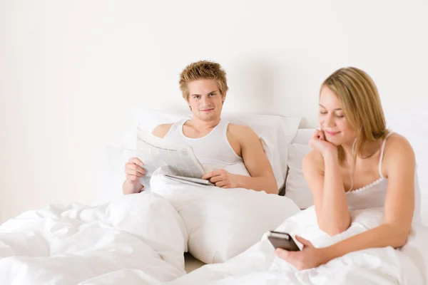 Mladý pár odpočívat v posteli poslouchat hudbu — Stock fotografie