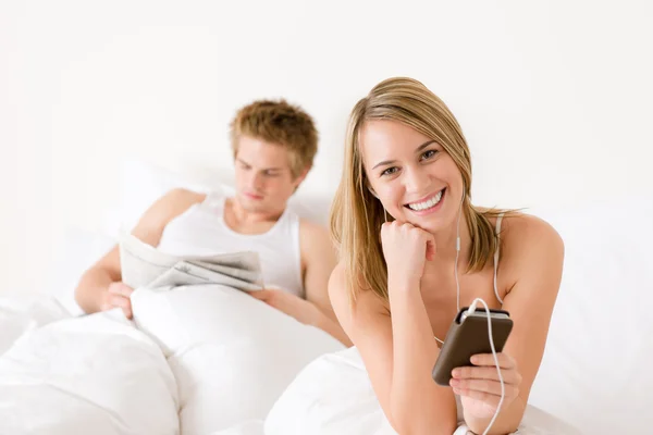 Junges Paar Entspannt Weißen Bett Musik Hören Zeitung Lesen — Stockfoto