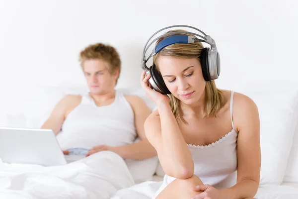 Jeune couple se détendre au lit avec de la musique et ordinateur portable — Photo