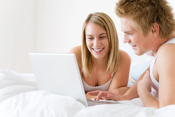 Jeune couple se détendre au lit avec ordinateur portable — Photo