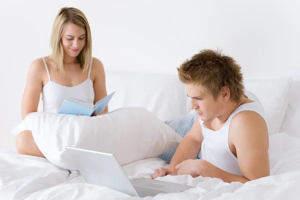 Jovem casal relaxar na cama com laptop — Fotografia de Stock