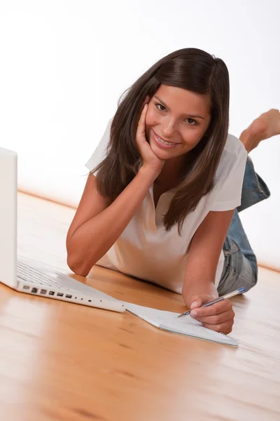 Adolescente sorrindo deitado com laptop — Fotografia de Stock
