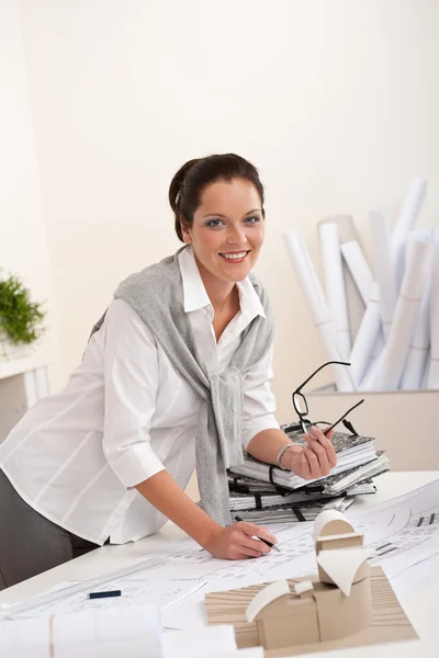 Arquiteta feminina sorridente com planos no escritório — Fotografia de Stock