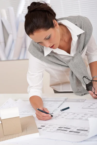 Vrouwelijke architect kijken plannen op kantoor — Stockfoto