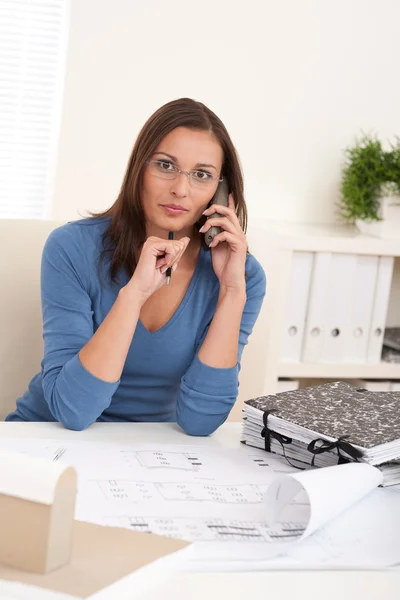 Leende kvinna arkitekten hålla telefonen och penna — Stockfoto