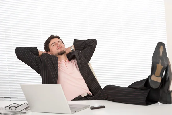 Успешный бизнесмен в черном костюме расслабляется в офисе — стоковое фото