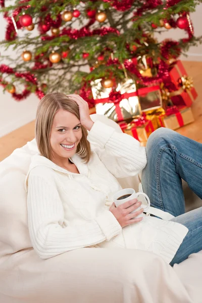 クリスマス ツリーの前でコーヒーを 杯とブロンドの笑顔の女性 — ストック写真