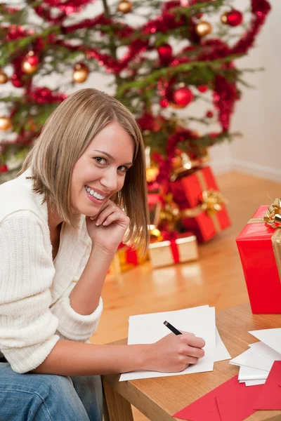 Ελκυστική ξανθιά γυναίκα γράφοντας Χριστουγεννιάτικες κάρτες — Φωτογραφία Αρχείου