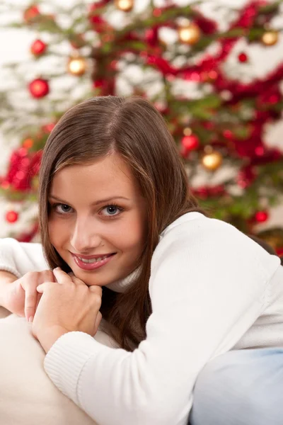 Χαμογελώντας η νεαρή γυναίκα μπροστά από το χριστουγεννιάτικο δέντρο — Φωτογραφία Αρχείου