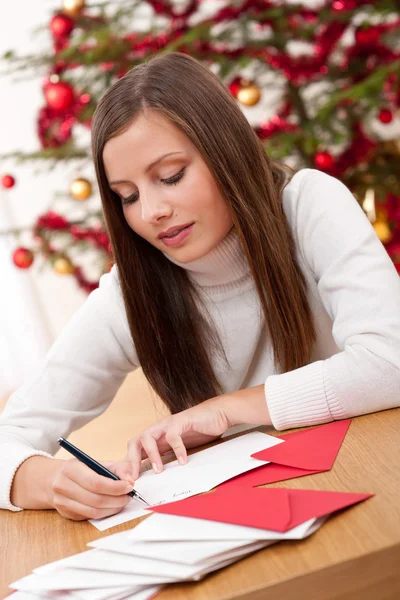 ツリーの前でクリスマス カードを書く若い女性 — ストック写真