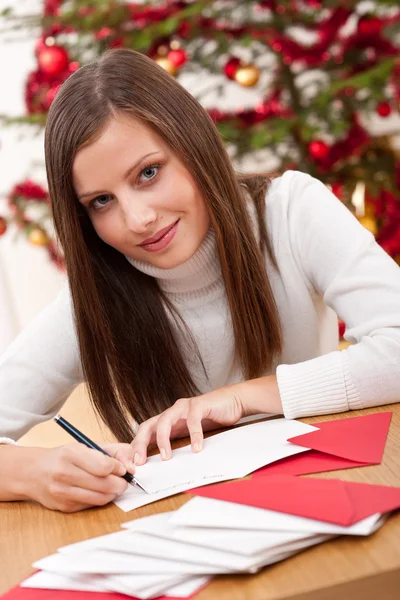 Νεαρή γυναίκα σκέφτεται γράφοντας Χριστουγεννιάτικη κάρτα — Φωτογραφία Αρχείου