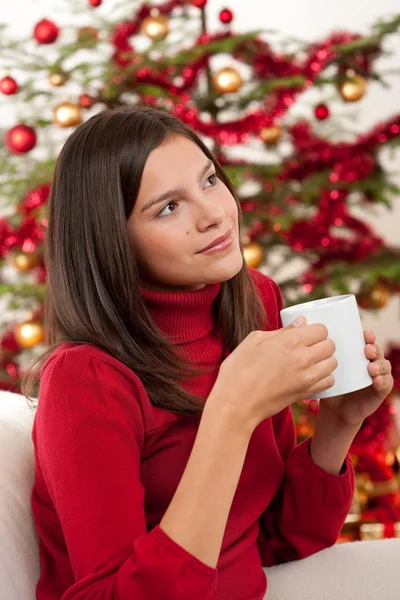 stock image Attractive brunette in front of Christmas tree holding cup of coffee