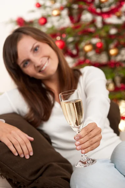 クリスマス ツリーの前にシャンパンのグラスを持つ若い女 — ストック写真