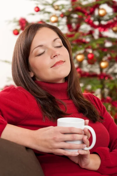 Bruin haar vrouw ontspannen voor kerstboom — Stockfoto
