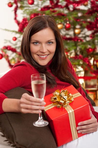 웃 고 있는 크리스마스 선물을 가진 여자와 샴페인의 유리 — 스톡 사진