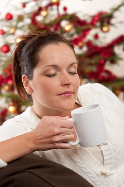 クリスマス ツリーの前でコーヒーを 杯とリラックスした茶色の髪の女性 — ストック写真