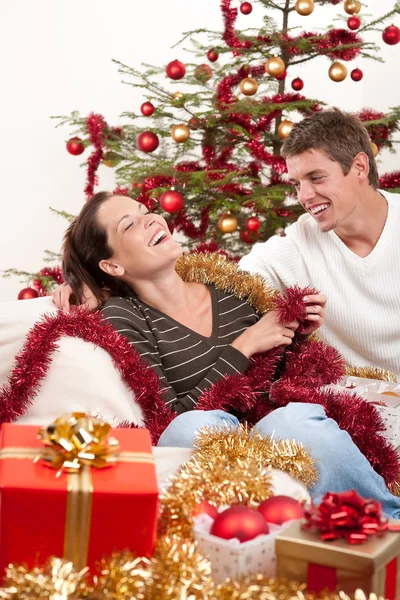 Νεαρό ζευγάρι, κάθονται, μαζί, μπροστά από το χριστουγεννιάτικο δέντρο — Φωτογραφία Αρχείου