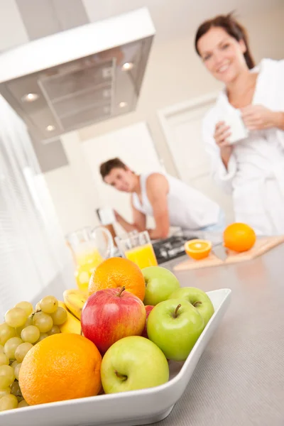 Bowl with fruits, couple in the background — Stock Photo, Image