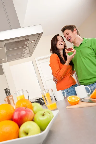 Young man and woman eating toast in the kitchen — Stock Photo, Image