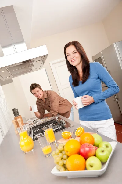 女と男の台所では コーヒー オレンジ ジュースを持つ笑みを浮かべてください — ストック写真