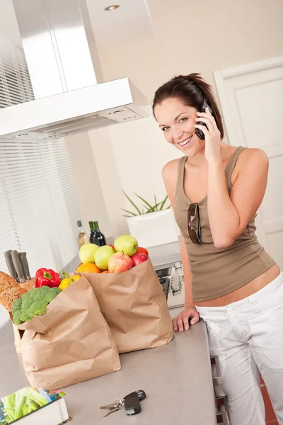 Unga leende kvinna med matvaror i köket — Stockfoto