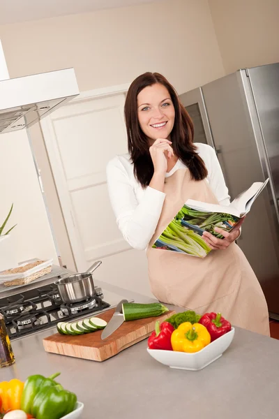 Улыбающаяся женщина держит поваренную книгу на кухне — стоковое фото