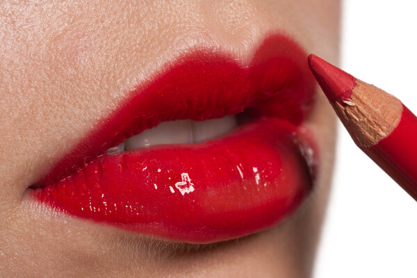 Close-up of red woman lips, applying lip pencil on white, macro lens