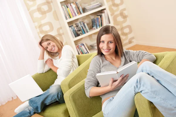 学习与便携式计算机和书的两个女性青少年在现代的客厅里 — 图库照片