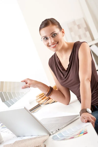 カラー見本とオフィスでラップトップと笑みを浮かべて女性デザイナー — ストック写真