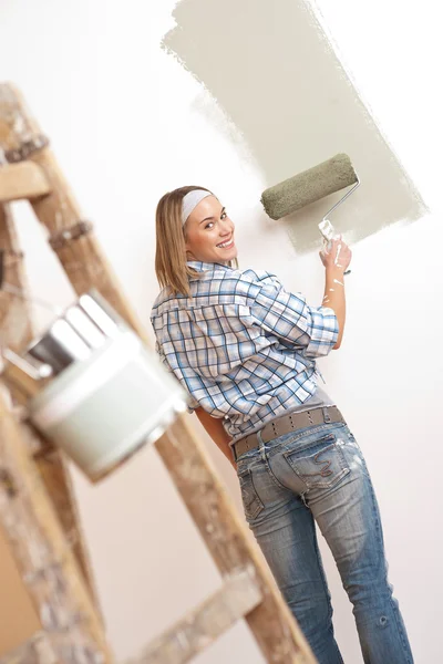 Благоустройство дома: блондинка рисует стену — стоковое фото
