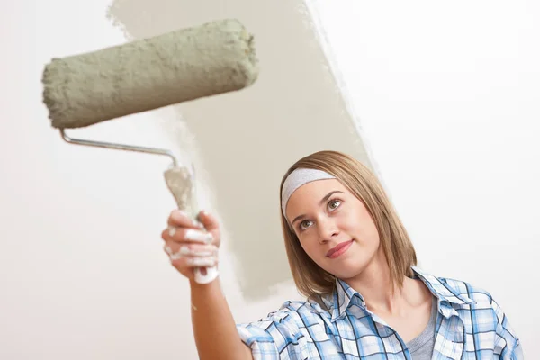 家里的改进 油漆滚筒绘画墙的年轻女子 — 图库照片