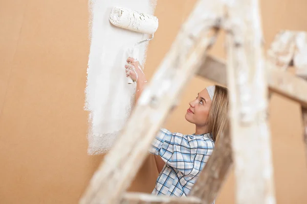 Улучшение дома: Женщина роспись стены с краской ролика — стоковое фото