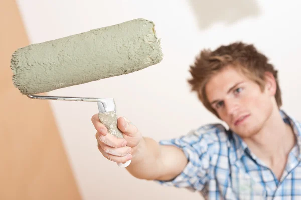 Renovering: ung man håller paint roller — Stockfoto