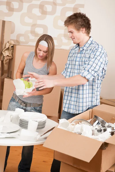 Casa em movimento: casal jovem desempacotando pratos de cozinha — Fotografia de Stock
