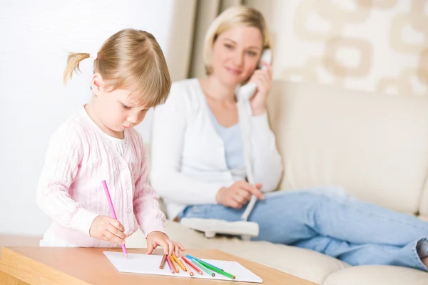 Маленькая Девочка Рисует Цветным Карандашом Гостиной Мать Телефоном Лицензионные Стоковые Фото