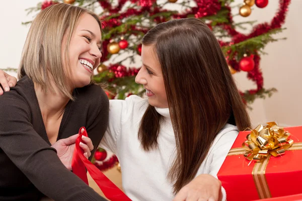 Twee Jonge Vrouwen Tegenover Kerstboom Glimlachen Stockafbeelding
