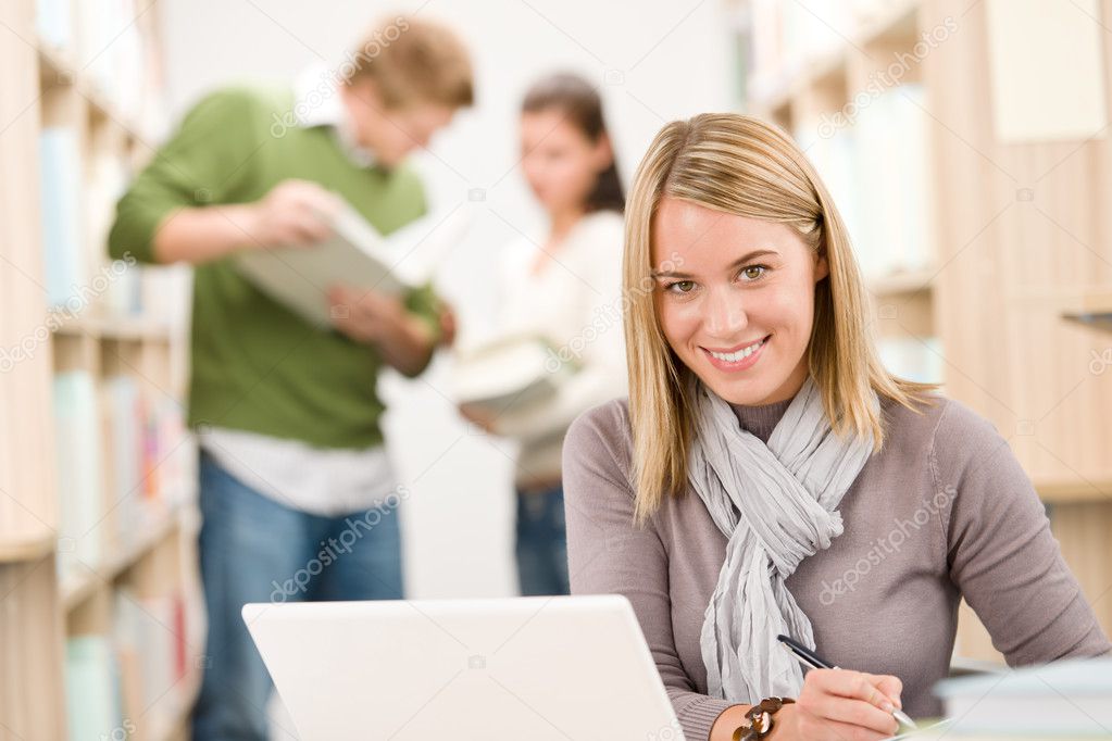 High school library - happy female student with laptop and book