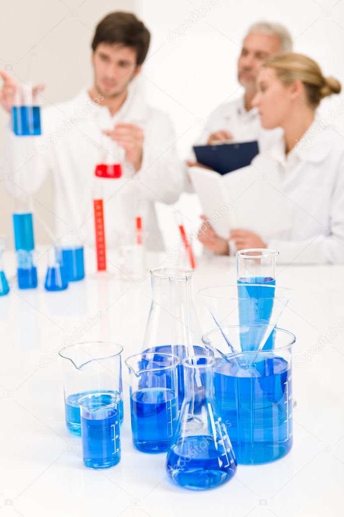 Laboratory - beaker with blue liquid, scientists in backgroud