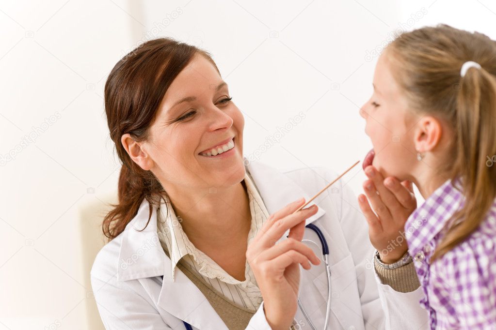 Female doctor examining child with tongue depressor