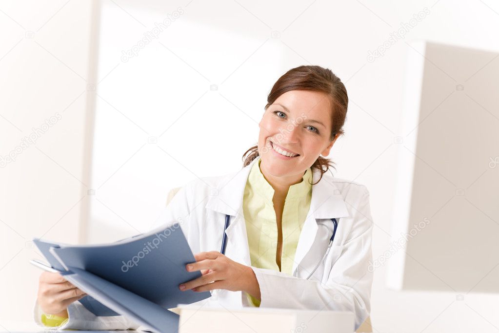 Female doctor at medical office with stethoscope reading files