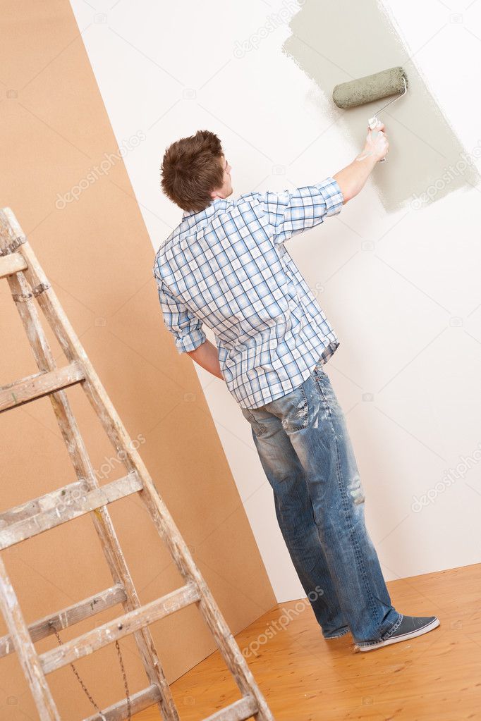 Home improvement: Young man with paint roller and ladder