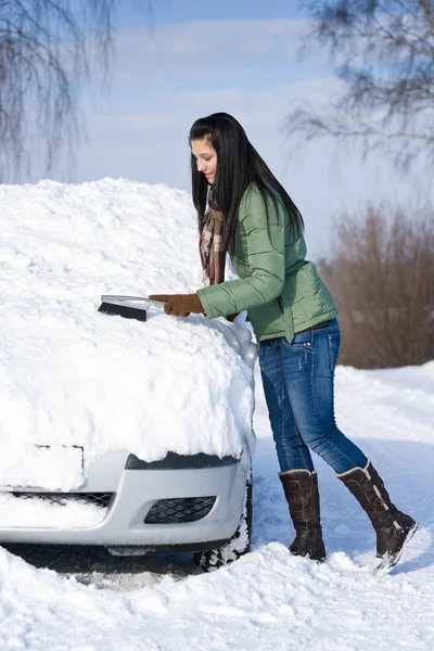 Winterauto - Frau räumt Schnee von Windschutzscheibe Stockfoto