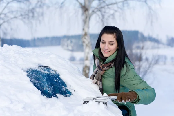 Winterauto - Frau räumt Schnee von Windschutzscheibe lizenzfreie Stockbilder