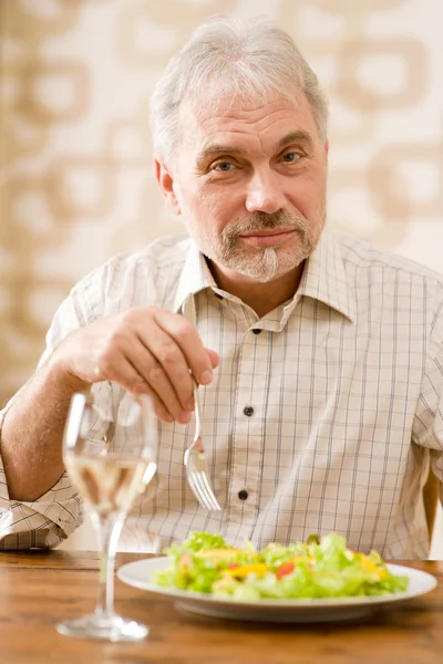 Старший зрілий чоловік їсть здоровий салат і біле вино — стокове фото