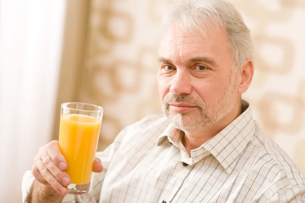 Senior mature man with glass of orange juice — Stock Photo, Image