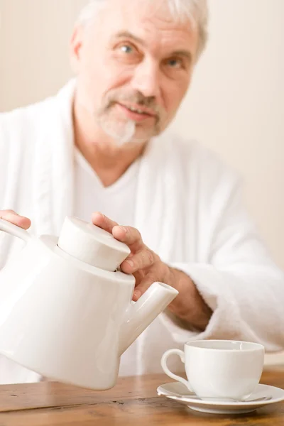 Starší zralý muž nalít kávu opotřebení župan — Stock fotografie