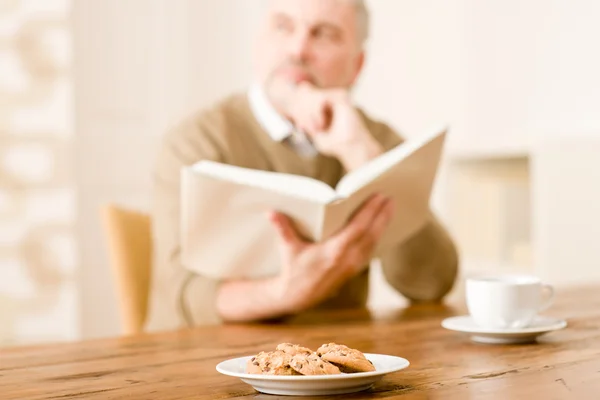 stock image Senior mature man, cookies at wooden table