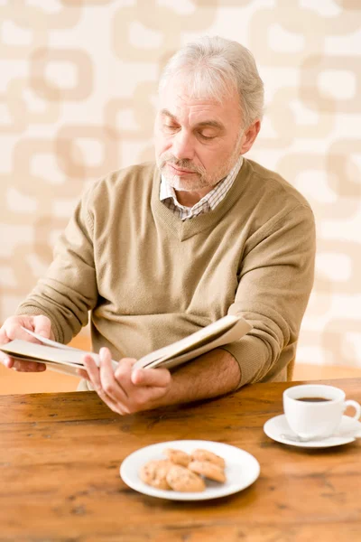 Sênior maduro homem leitura livro tendo café — Fotografia de Stock