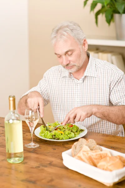 Senior uomo maturo mangiare insalata di verdure e vino bianco — Foto Stock
