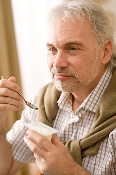 Älterer Mann isst Joghurt-Snack — Stockfoto